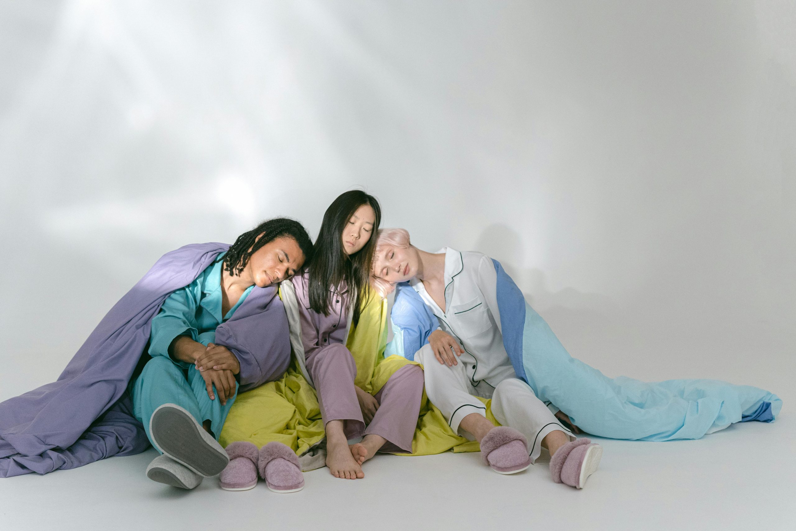 Relaxed group of three friends sitting on floor in colorful sleepwear.